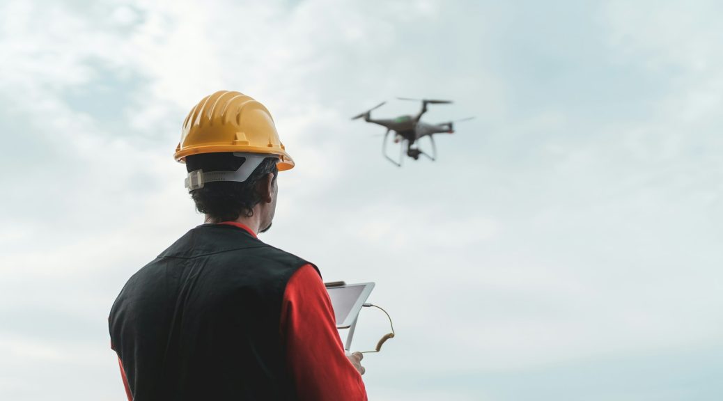 Male engineer monitoring construction site with drone - Technology and industrial concept